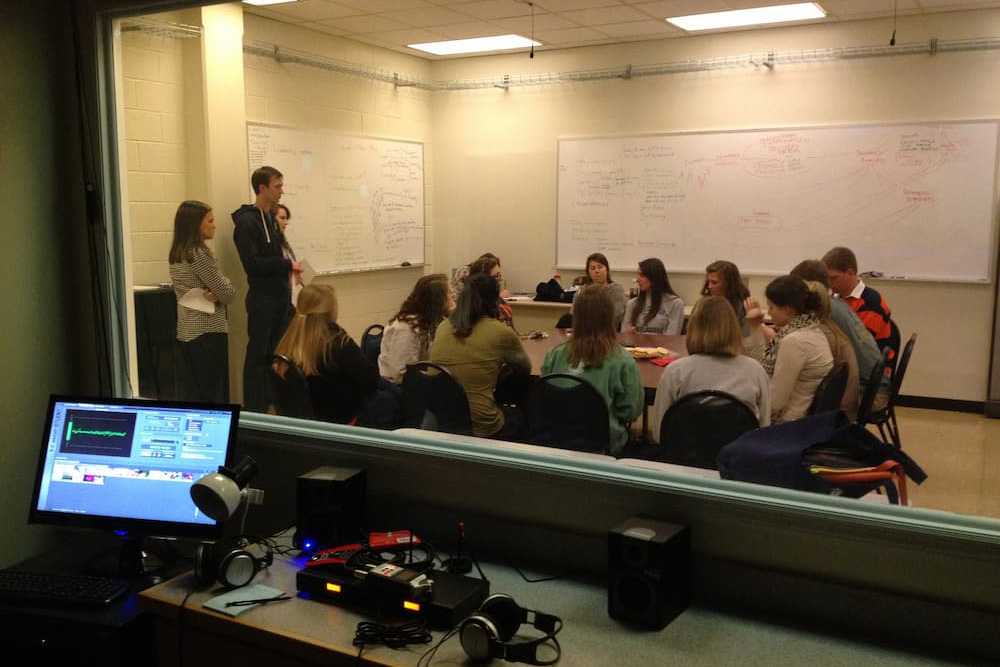 A photo taken from inside the LUCIA lab's control room that shows a focus group being conducted in the adjacent experimental room.