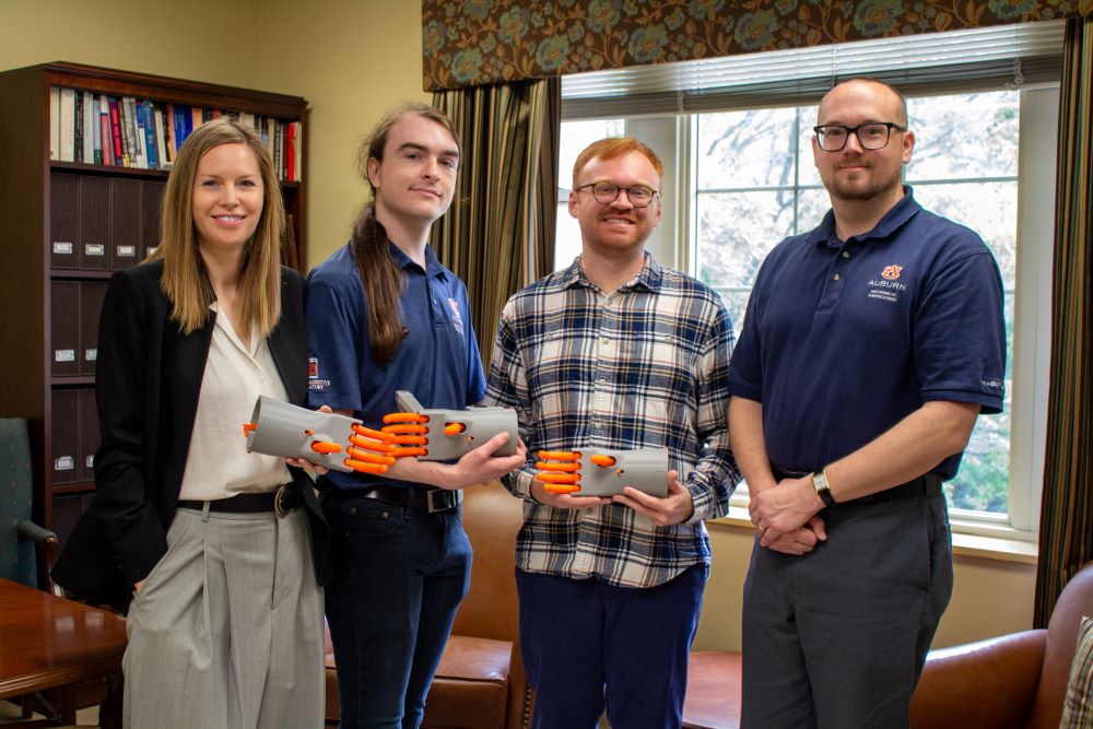 Heidi Hausse, Peden Jones, Stuart Simms and Chad Rose holding 3-D printed models of the Kassel Hand