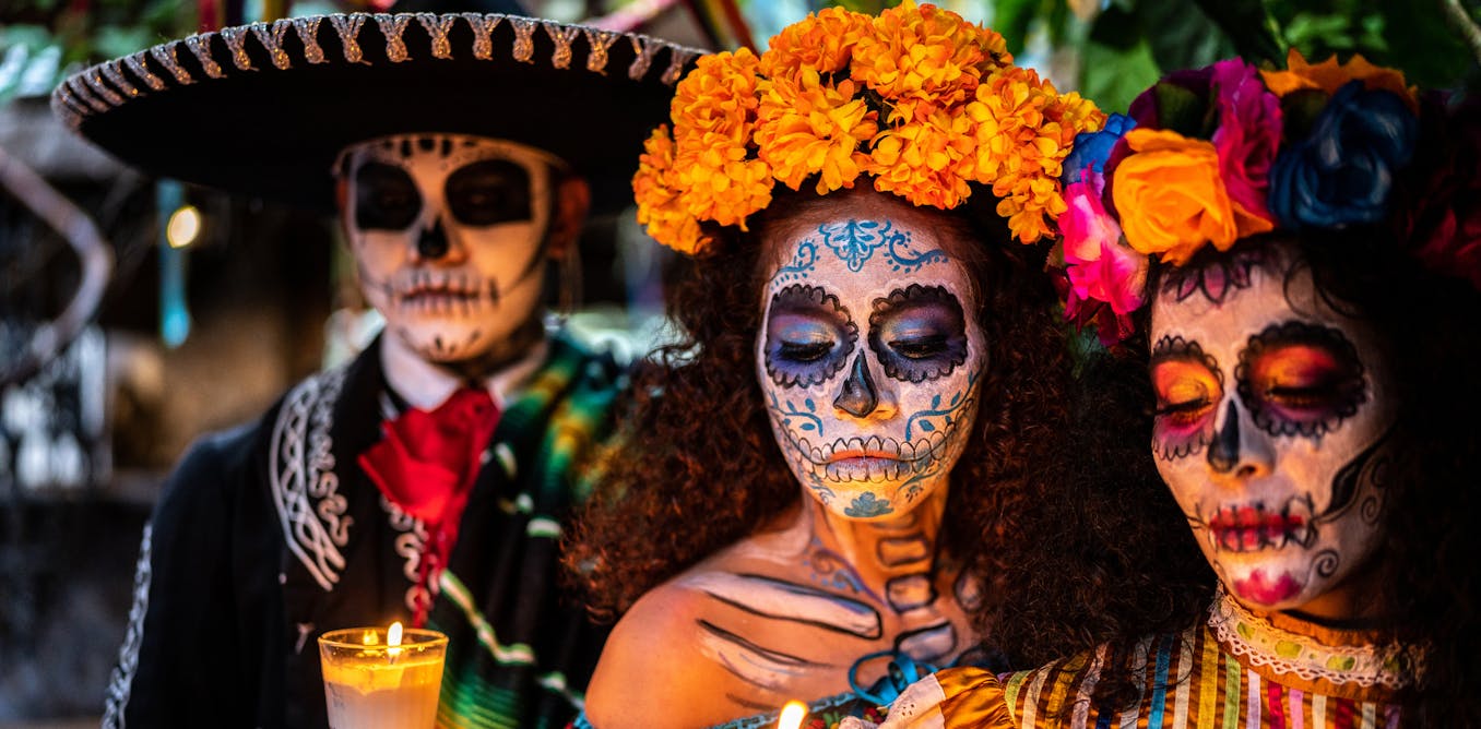 Three people dressed in traditional Dia de los Muertos (Day of the Dead) attire