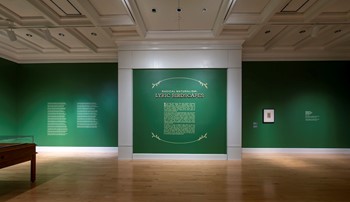Title wall of Radical Naturalism: Lyric Birdscapes. Walls are an emerald green with light gold text and surrounding leaf graphic elements and white trim