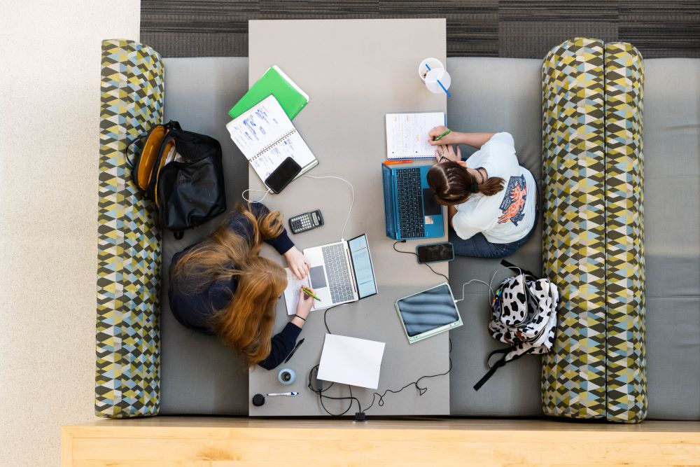 Aerial view of students using various electronic devices to complete coursework