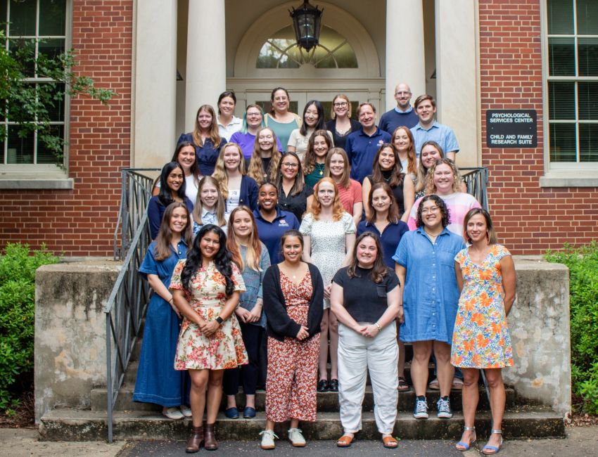 Group of people posing for a photo in front of a brick building