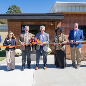 People cutting a ribbon in front of a building