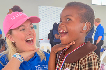 caylyn turner poses with young girl wearing hearing aid