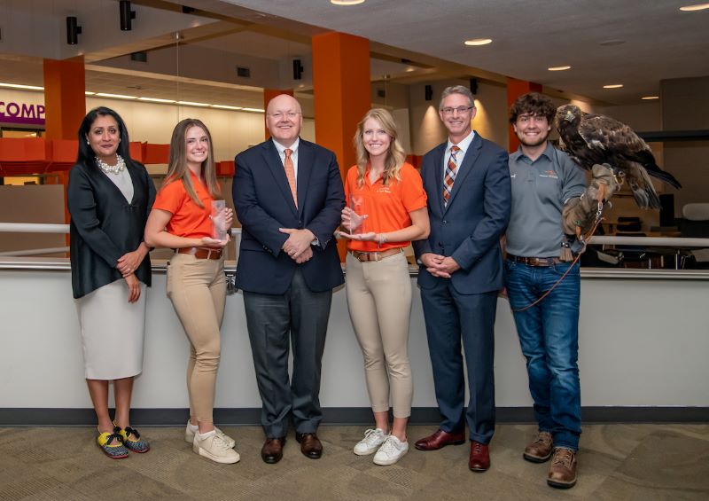 Interim Provost Vini Nathan, Elizabeth Moorman, President Chris Roberts, Maggie Hearn, Dean Jason Hicks, Blake Bohannon and Nova pose with Iron Eagle Awards