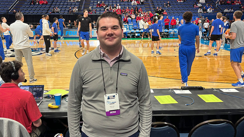 Daniel Locke posing for a photo courtside at the NCAA men's basketball tournament