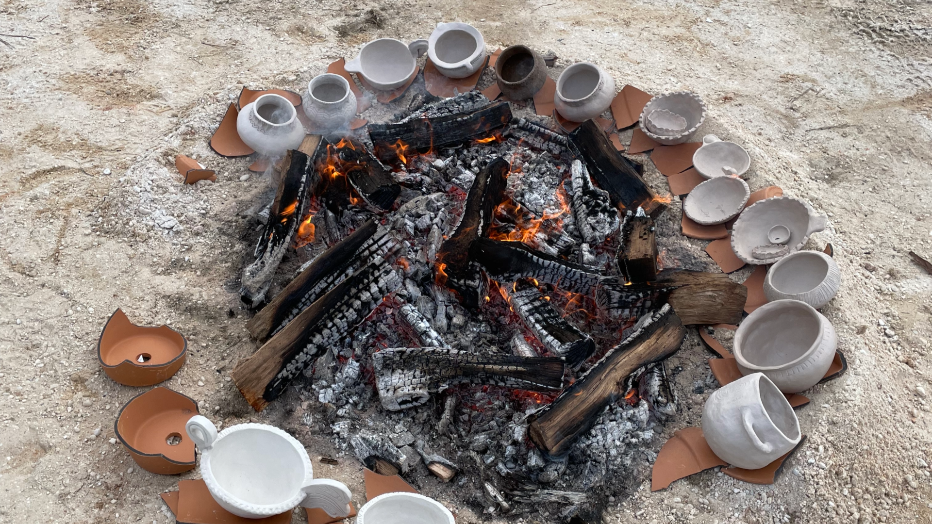 Image of the coals of a fire surrounded by clay pots 