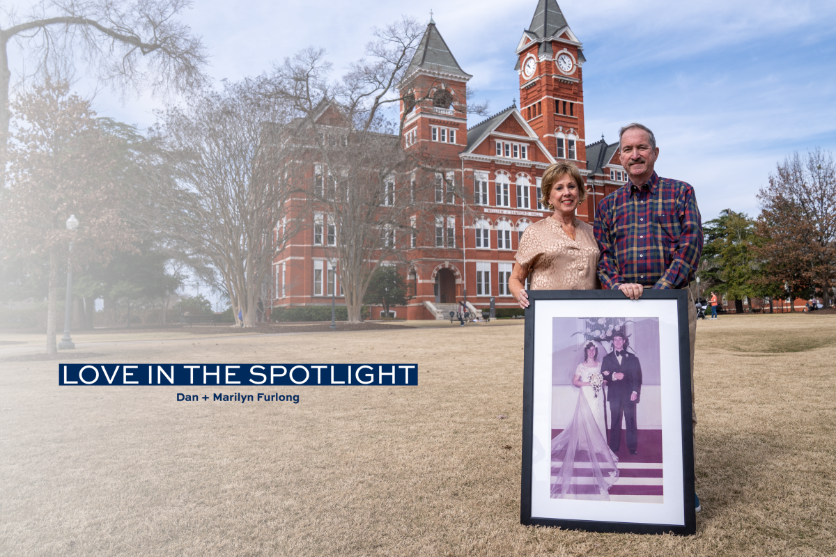 Dan and Marilyn Furlong stand in front of Samford Hall holding a photo from their wedding