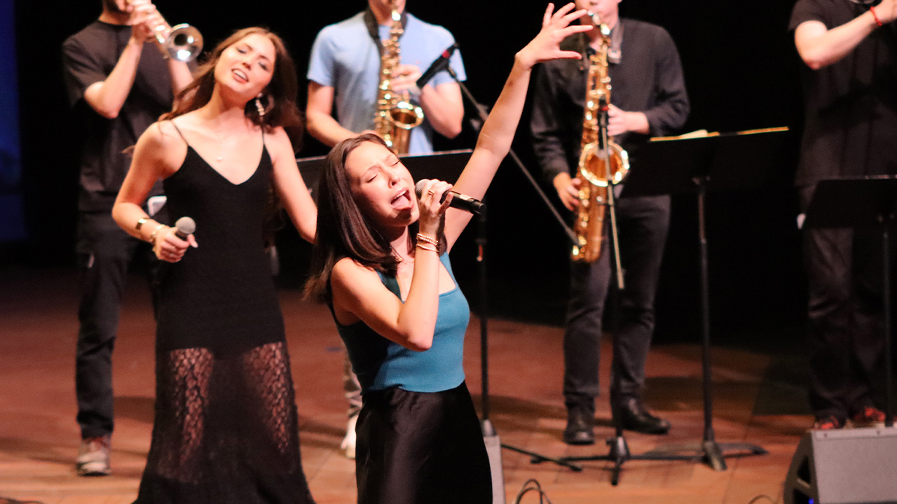 Anna Colson singing into a microphone during a performance