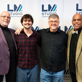 Four people standing in front of a banner with the Lucky Man Studio logo on it