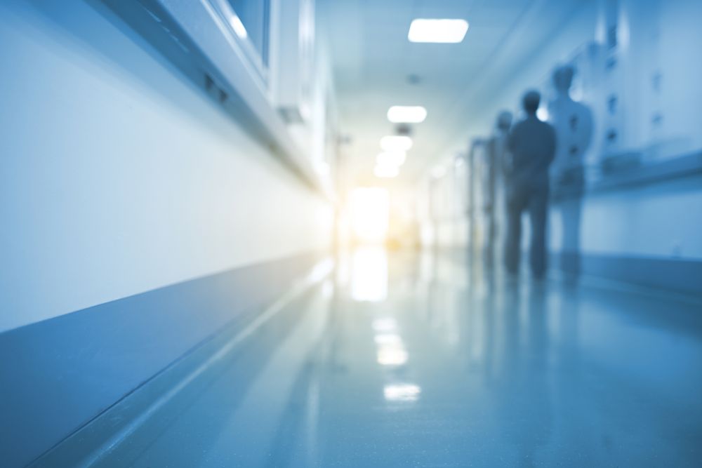 A silhouette of a medical professional walking down an unfocused hospital hallway