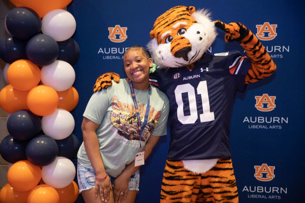 Student posing for a picture with Auburn's mascot, Aubie