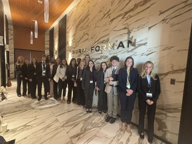 Group of students standing along a wall with the name Burr &amp; Forman displayed on it