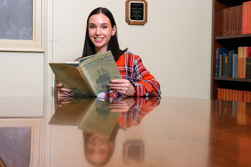 Emma Bond reads The Grand Expedition, a book written by her grandfather, inside the Gordon Crews Bond library