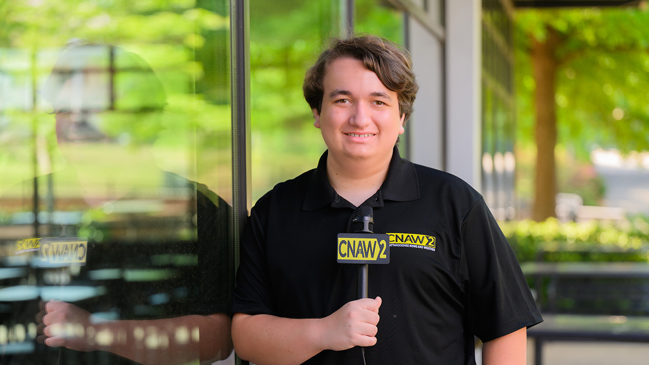 Colin Scroggins holding a CNAW2 News microphone