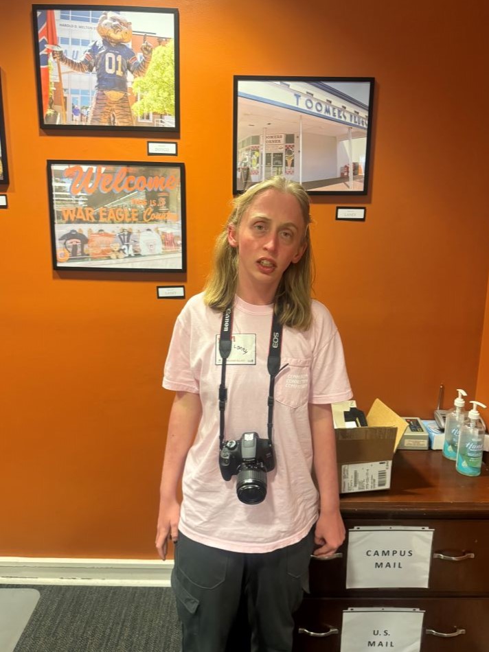 Braveheart artist Laney standing beside photos of Toomer's Corner