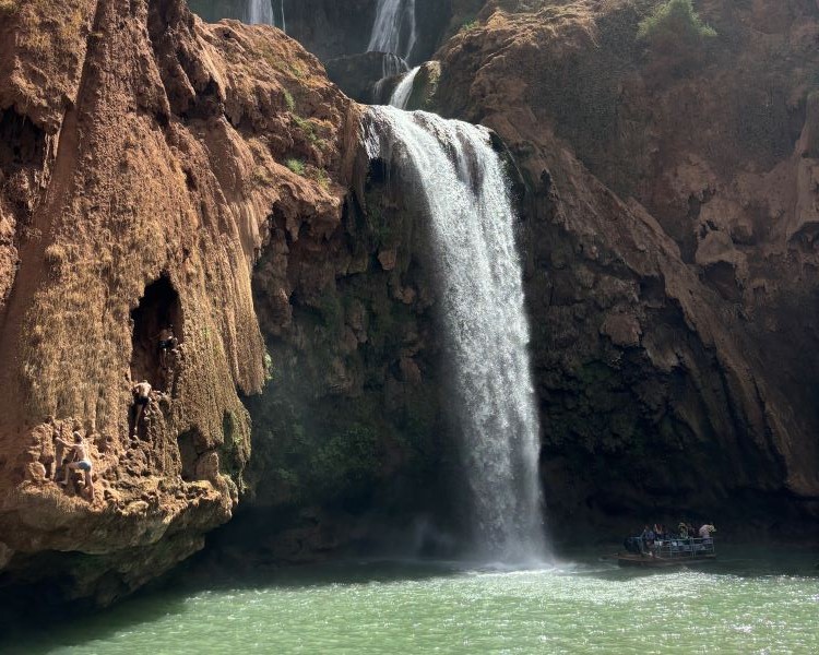A waterfall rushing over large rocks into a pool