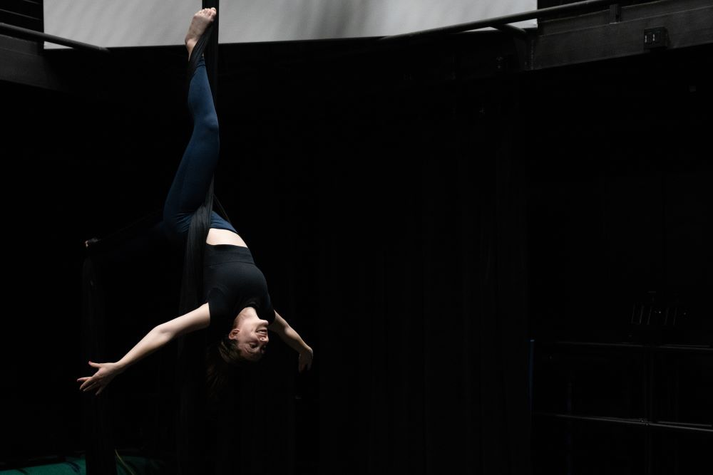 Sydney Pereira hanging upside down on aerial fabrics
