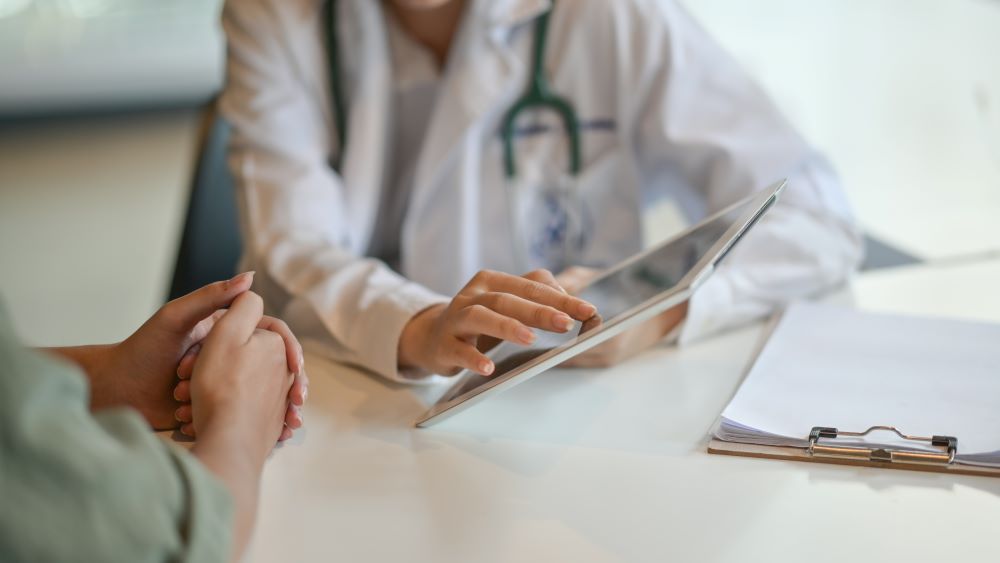 Patient listening as a doctor points at information on a digital tablet
