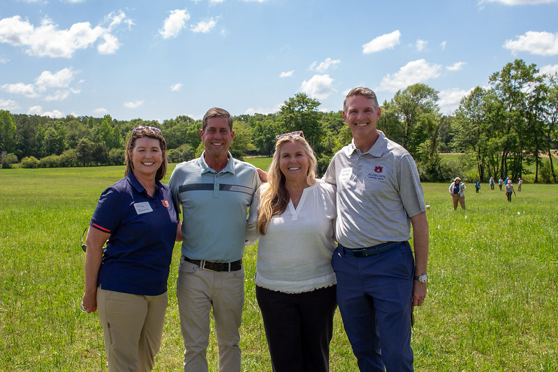 Four people standing in a field posing for a photo