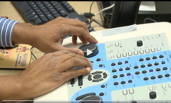 a pair of hands operate audiology testing equipment