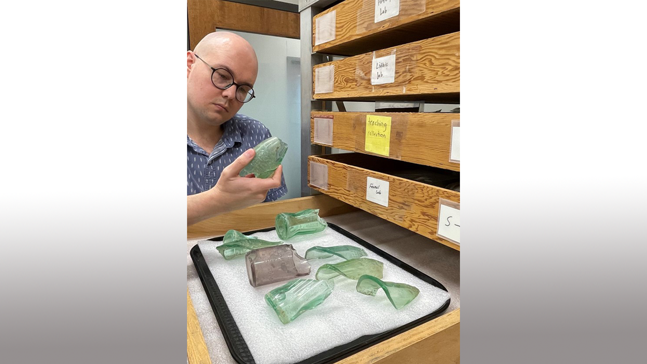 Nickolas Long examining broken bottles on a lab table