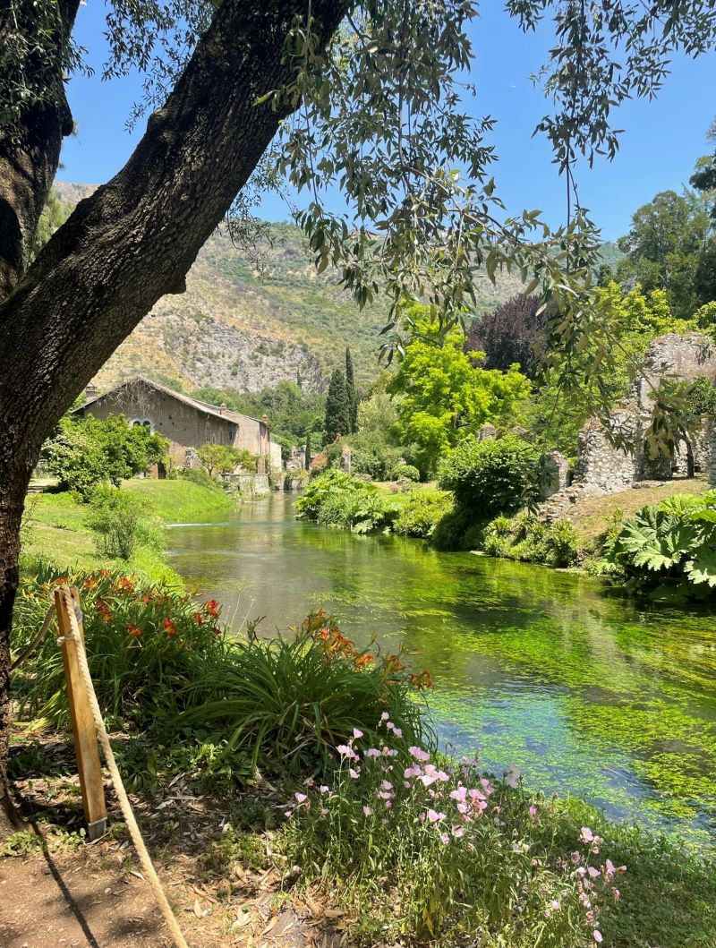Italian countryside house with small river and mountains in background
