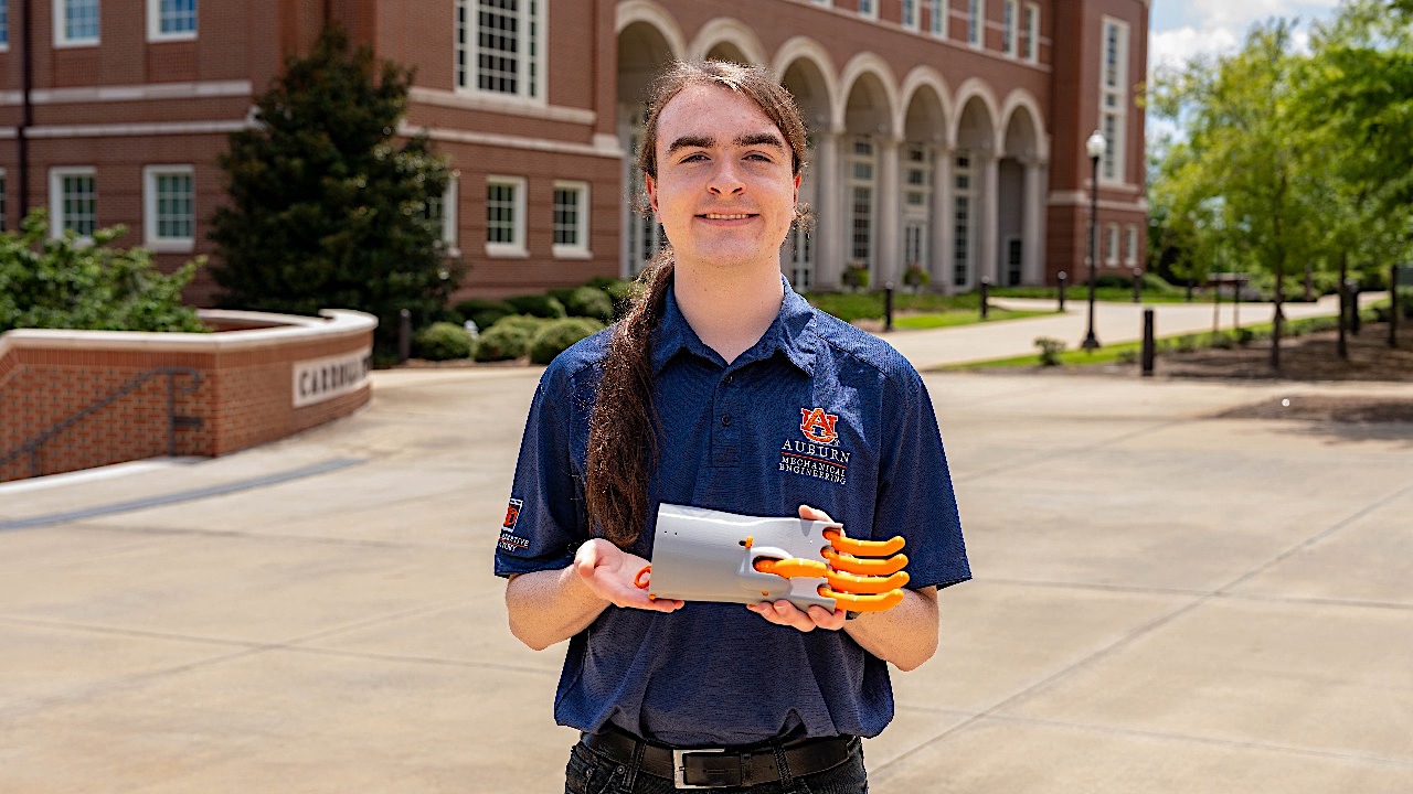 Peden Jones holding a 3-D printed recreation of a 500-year-old mechanical hand