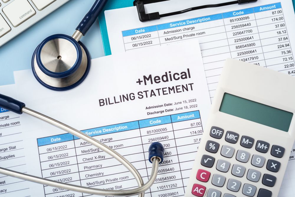 Expensive medical bills crowding a tabletop alongside a calculator and stethoscope