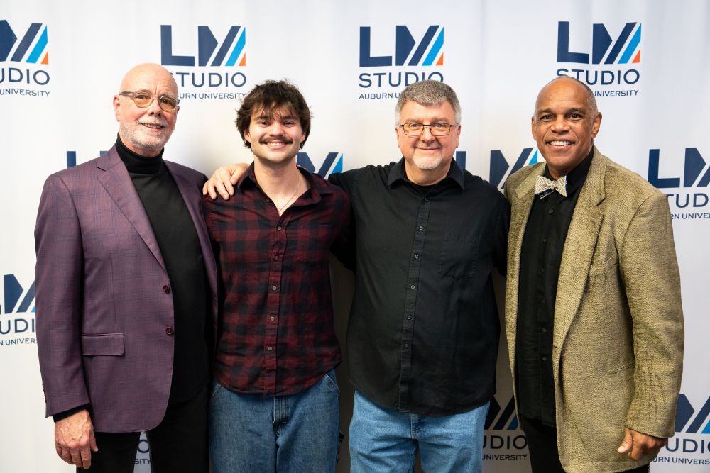 Four people standing together in front of a Lucky Man Studio logo backdrop