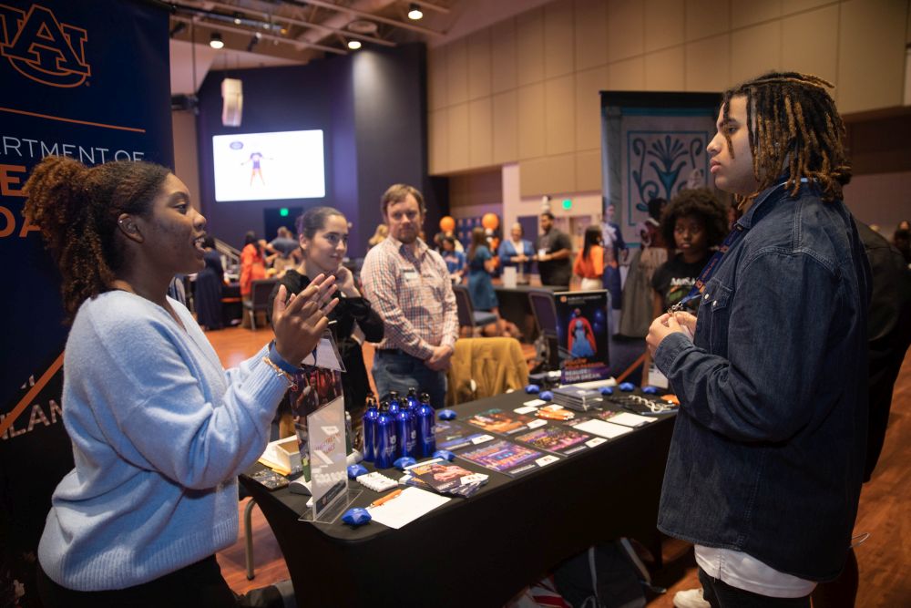 student standing near a table talking to a woman