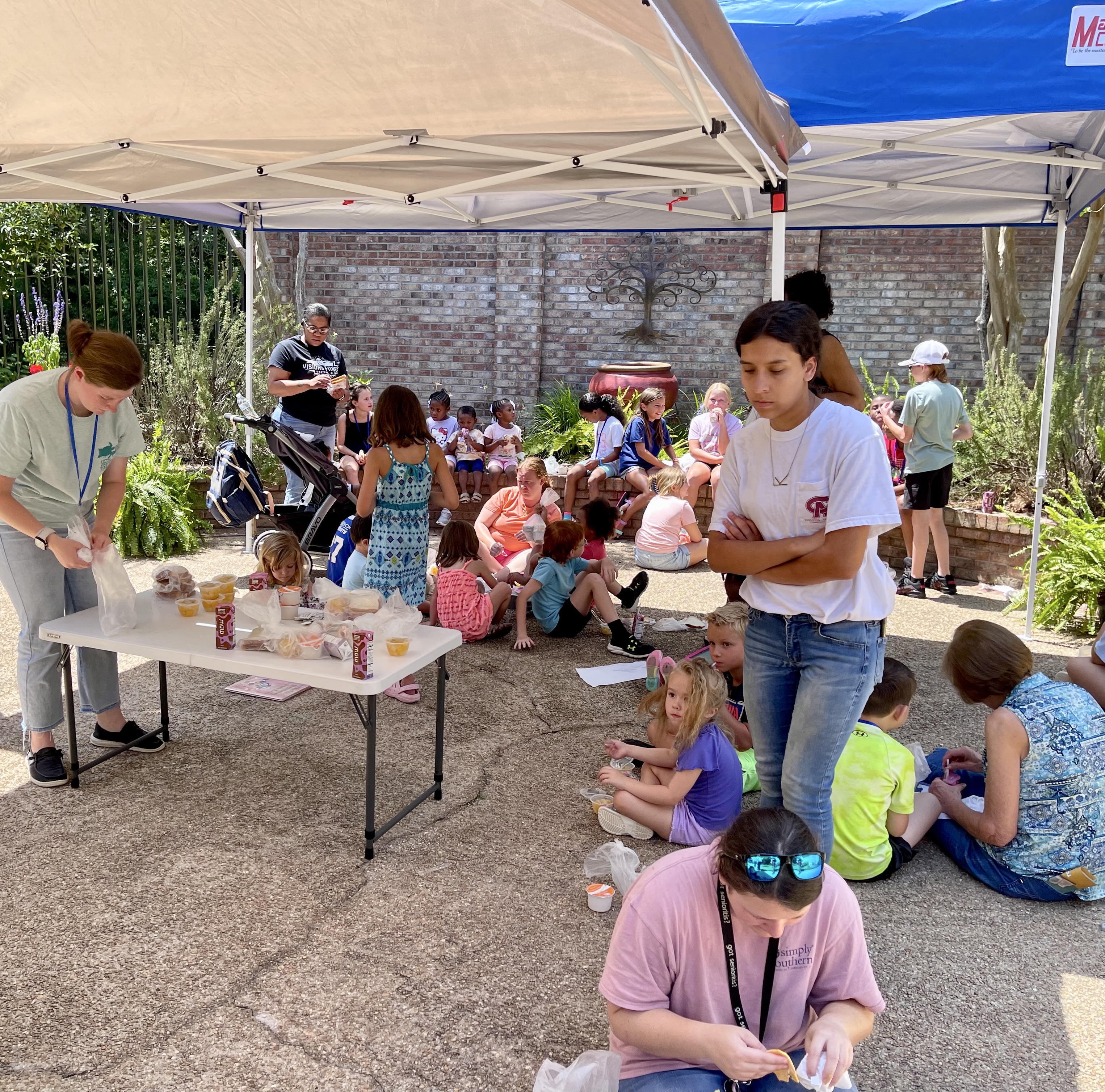 Children gather under the tents at the Washington County Public Library courtyard to eat lunch after a Summer Learning Program session. Contributed by Beth Roney