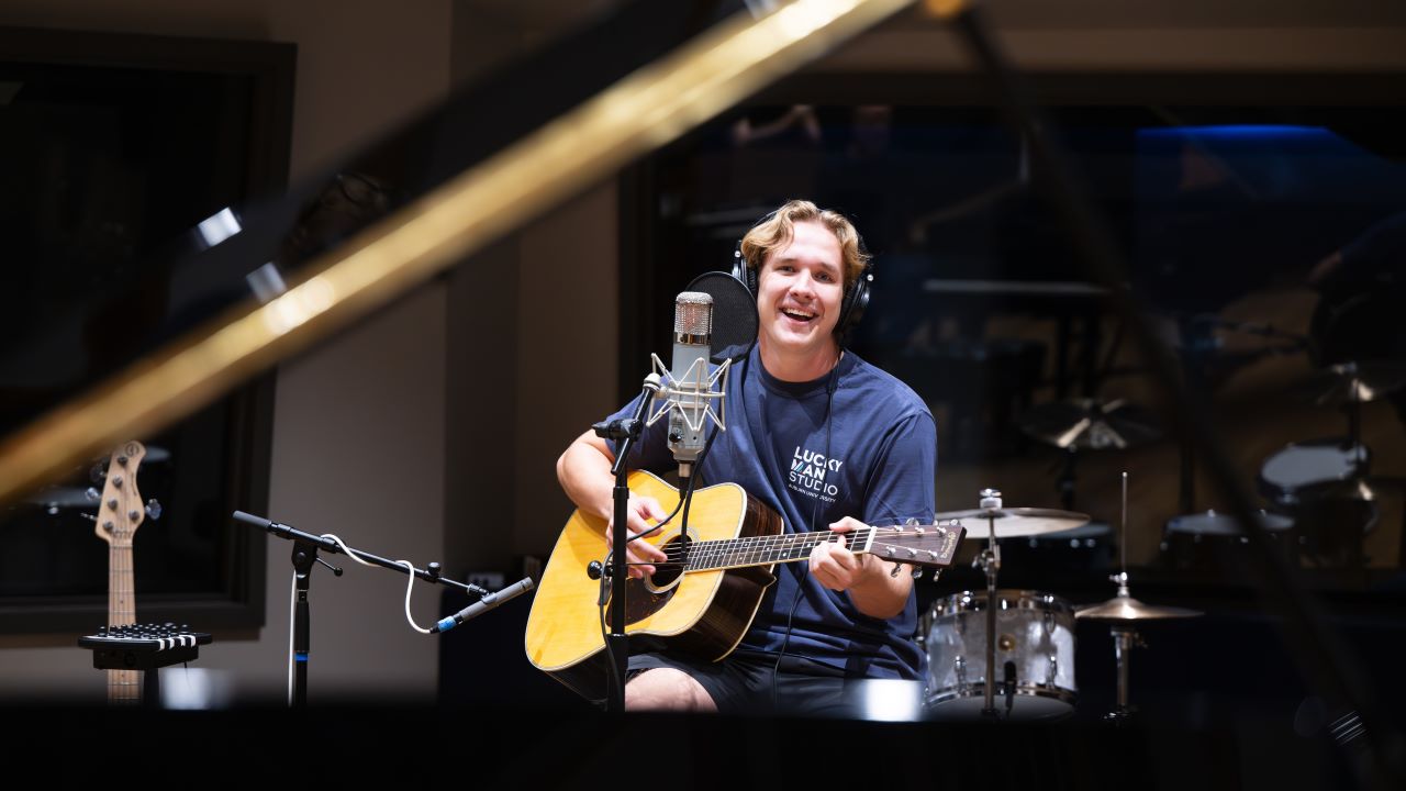 Student playing guitar and recording a song in the Lucky Man Studio