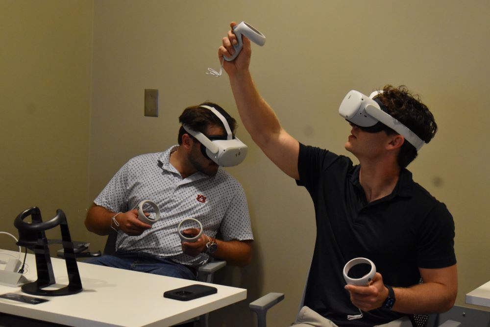 Two students using VR headsets and remotes to conduct virtual flight checks