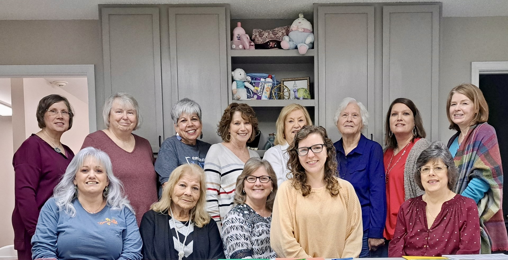 Women pose together at the front desk of Alpha