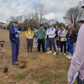 Students standing together outdoors talking to a man