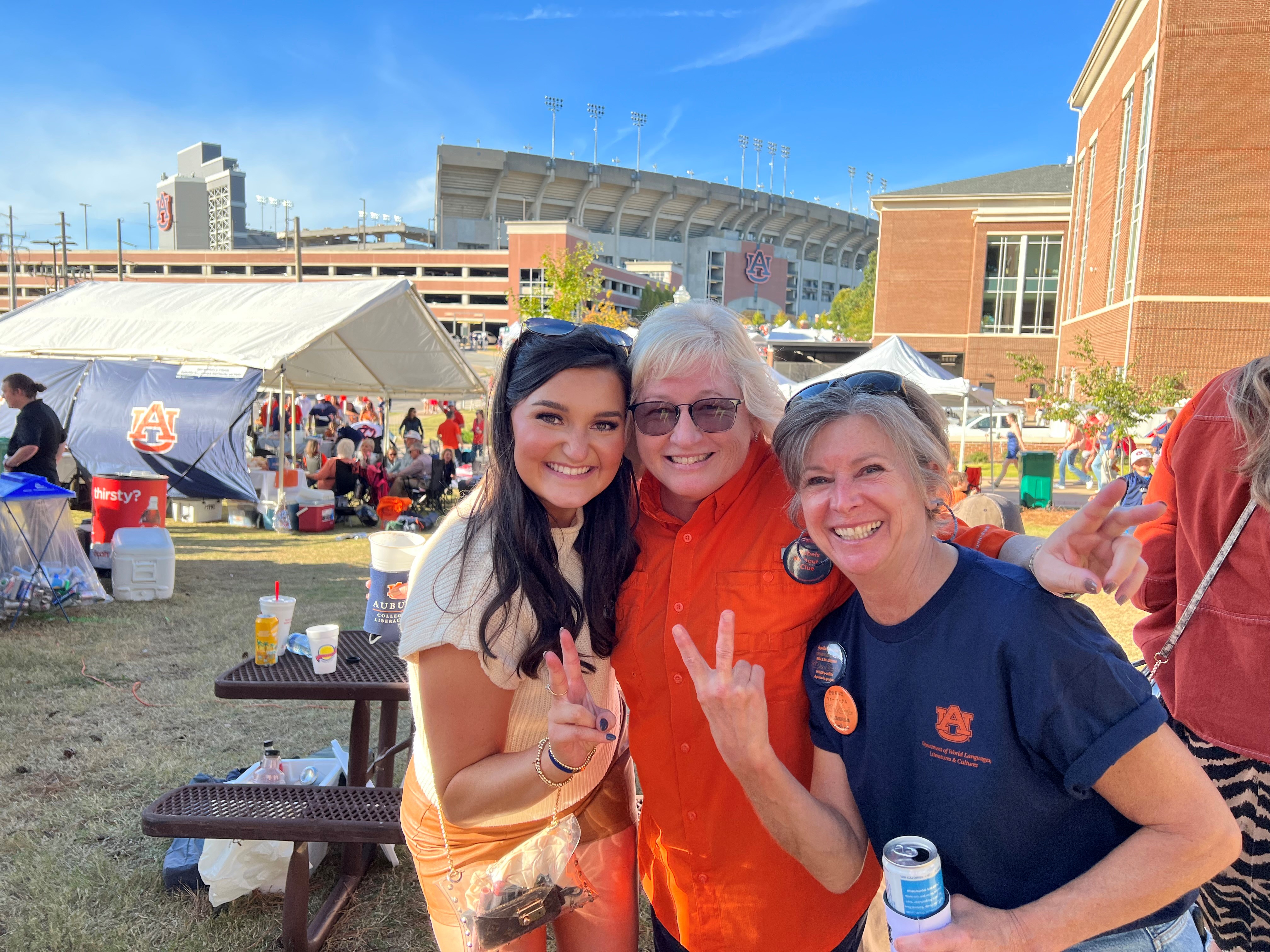 cheerful photo of three women posing together at an outdoor event, 