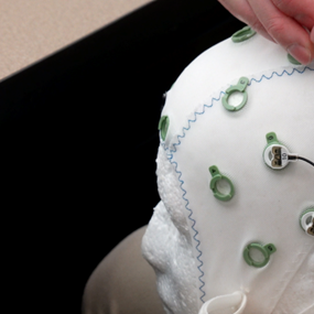 Richard Macatee fits brain sensors to a skull cap in the lab