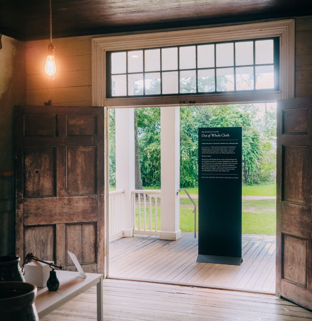 The Out of Whole Cloth exhibit sign standing in the doorway of a plantation house