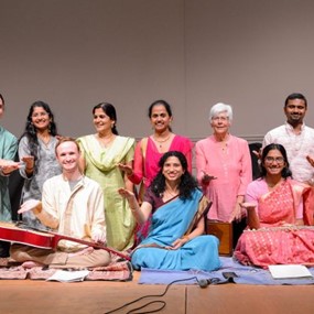 Group of people standing on a stage with indian music instruments