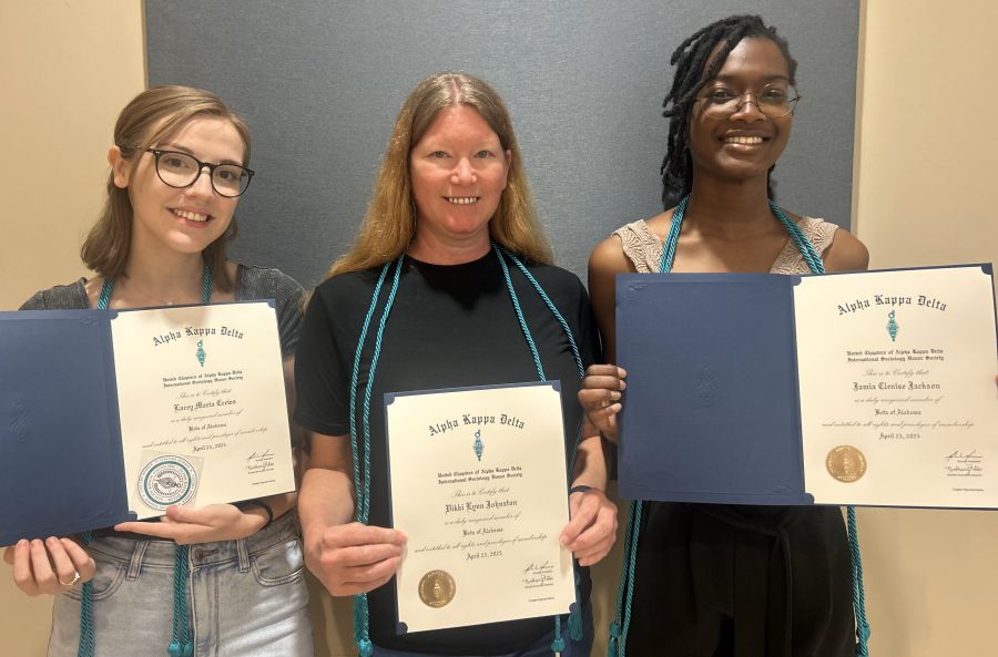 three female students standing together holding award certificates 