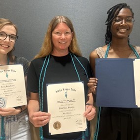 three female students standing together holding award certificates 