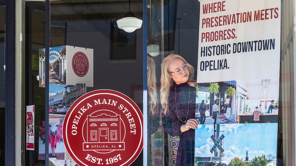 executive director of Opelika Main Street Kelsey Sullivan hanging a sign about historic preservation
