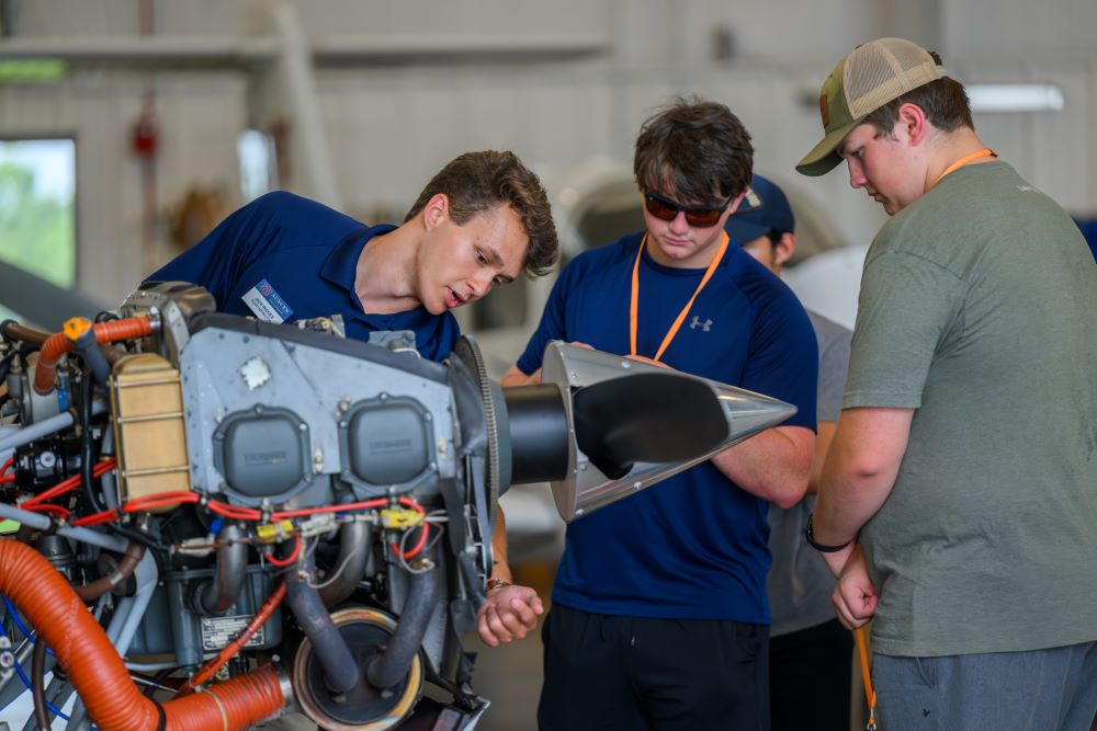 Auburn aviator pointing to parts of a plane engine