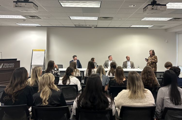 Students sitting in a room listening to a panel of professionals speak