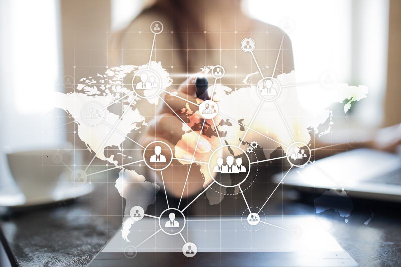 person pointing an ink pen at a screen featuring a world map