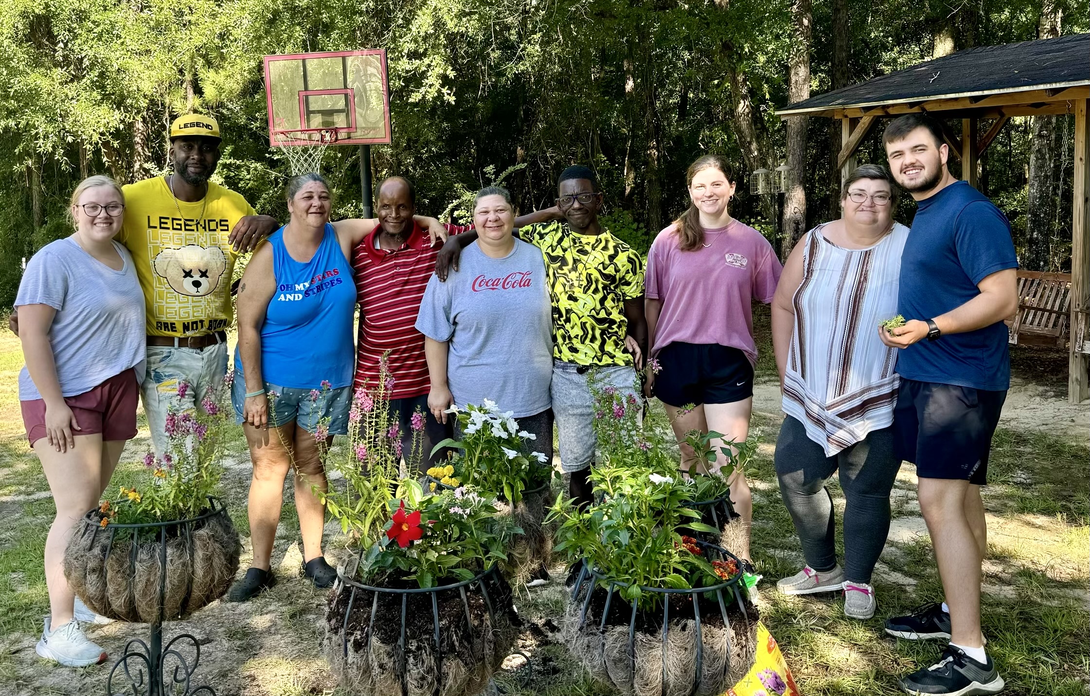 Residents help Haley Platt plant flowers at the the Arc of Southwest Alabama in Chatom.