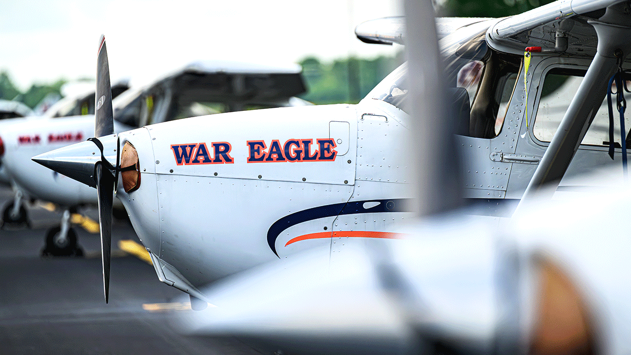 An Auburn-branded training aircraft sits on the runway, reflecting the real-world aviation context at the center of Physics for Aviators.