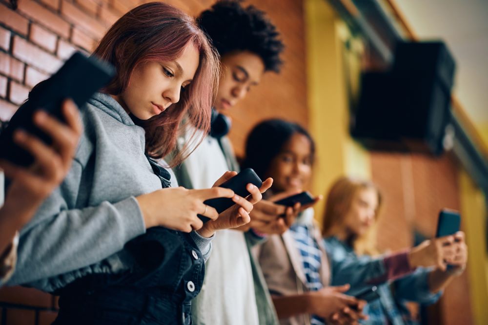 High school students using cell phones in hallway