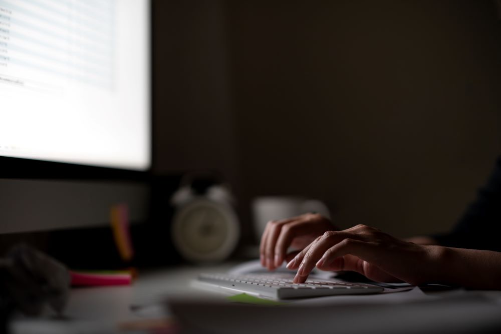 Person sits at a desk answering emails in a dark room